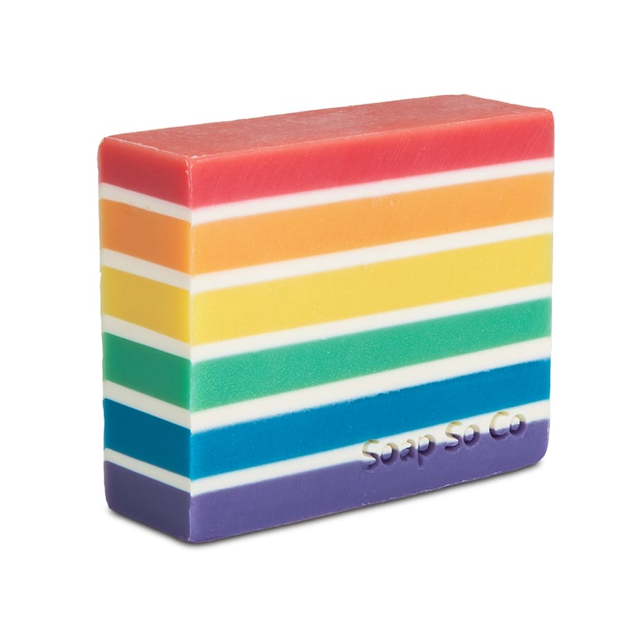 A rectangular bar of Soap So Co. soap with horizontal rainbow stripes, each in a different color, featuring embossed text that reads