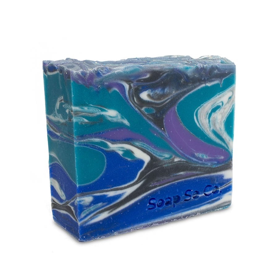 A lively bar of soap featuring swirling patterns in hues of blue, teal, purple, black, and white. The top has a slightly rugged texture and is embossed with the text 