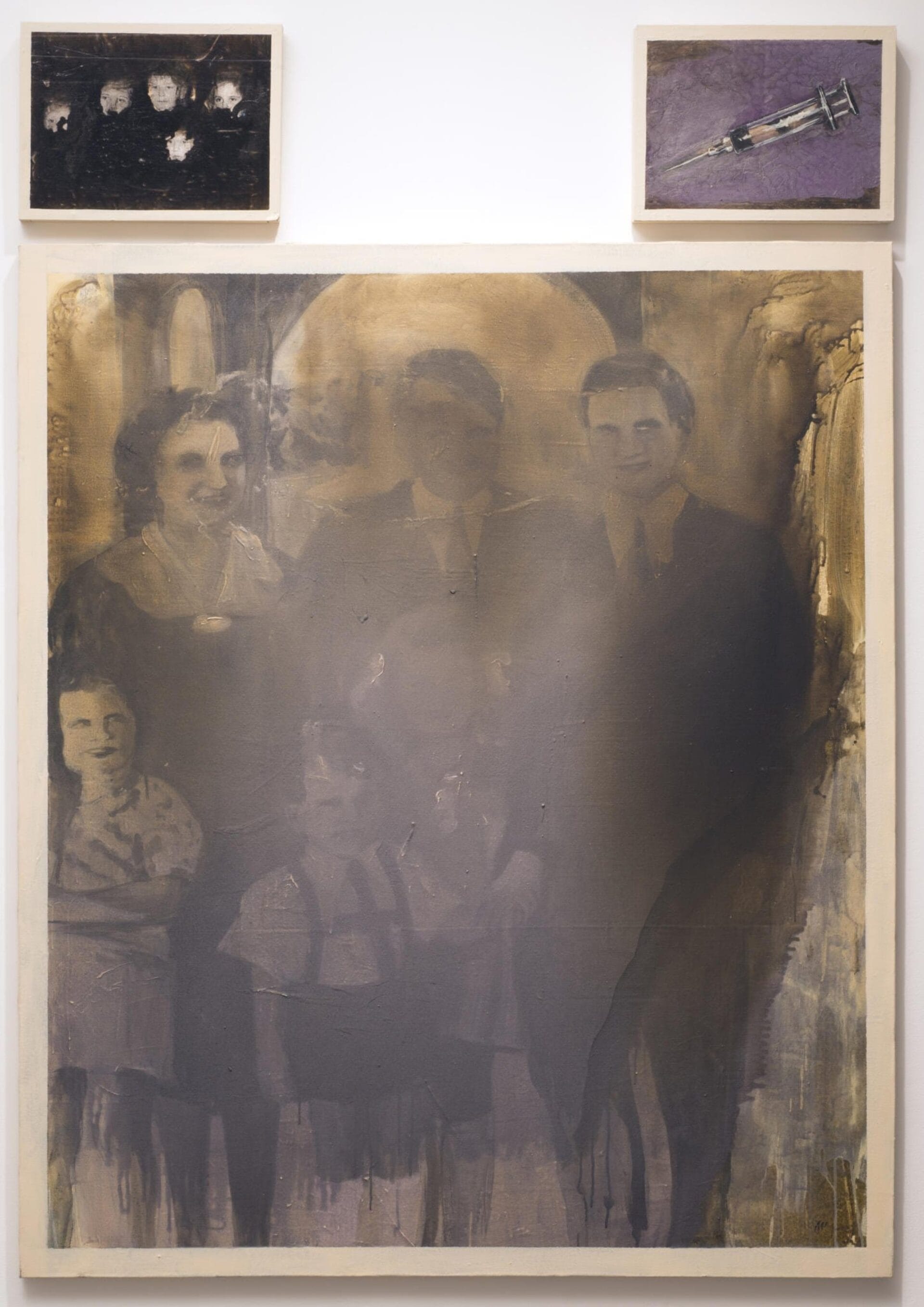 A large painting features a foggy, sepia-toned depiction of a family from the mid-20th century. Above it are two smaller pieces: one shows a vintage family photo, and the other depicts a syringe. The overall atmosphere is somber and haunting.