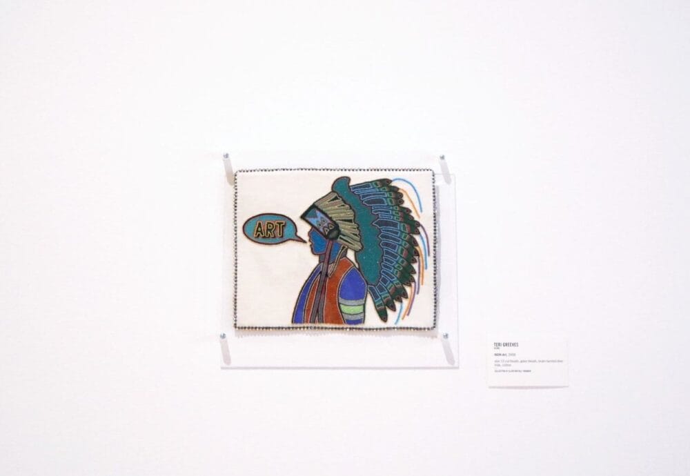 A framed artwork depicts a stylized profile of a figure wearing a detailed, colorful headdress, with the word 