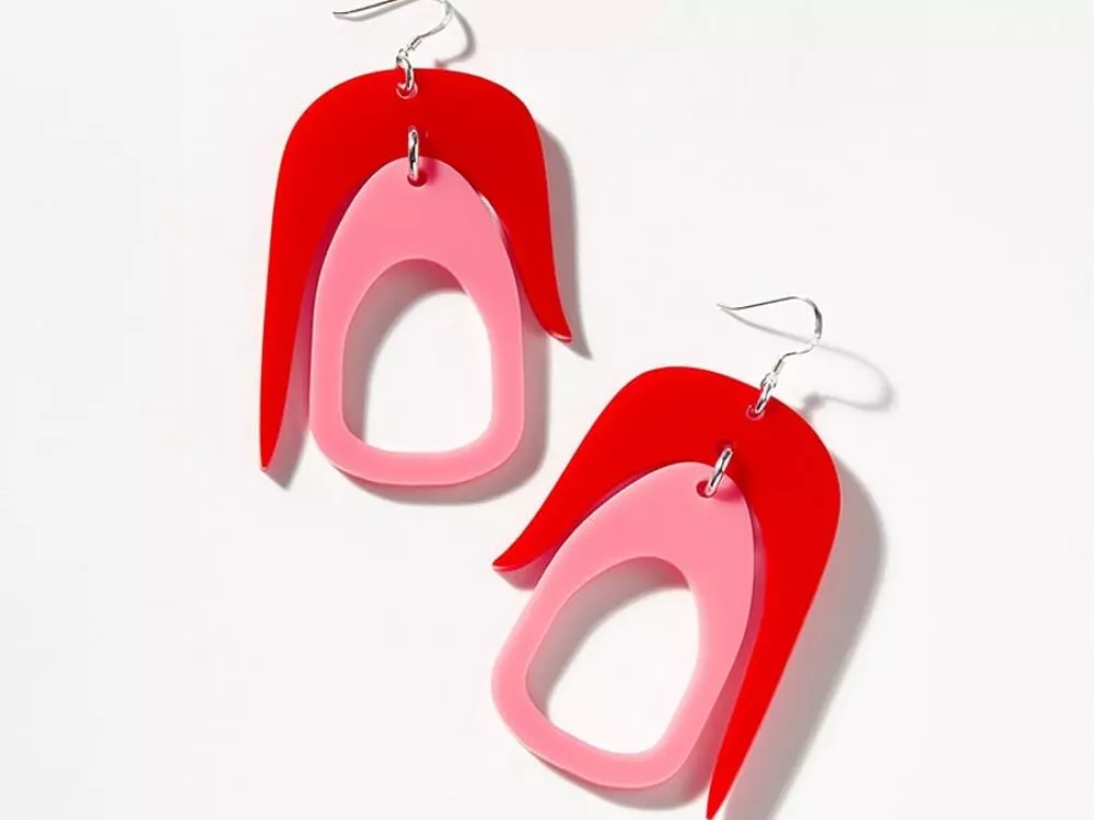 Introducing the Warren Steven Scott Earrings, a vibrant pair adorned with overlapping red and pink abstract shapes, complete with silver hooks, all showcased beautifully on a plain white background.