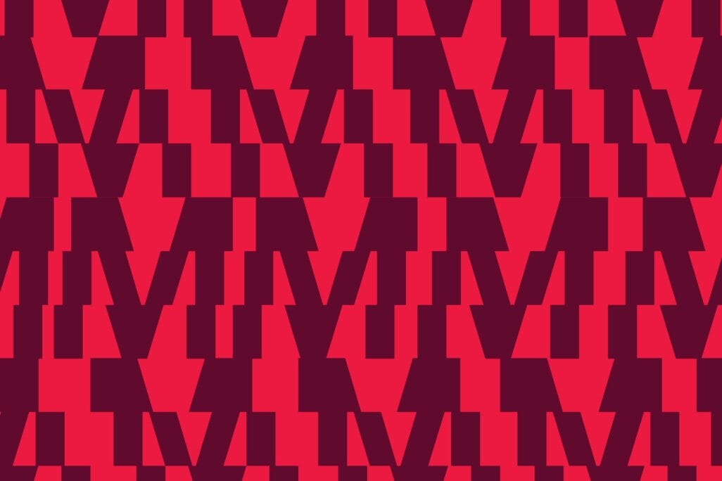 A repeating geometric pattern with dark red angular shapes on a bright red background. The shapes resemble interlocking M's or zigzag forms, creating a bold, visually striking effect.