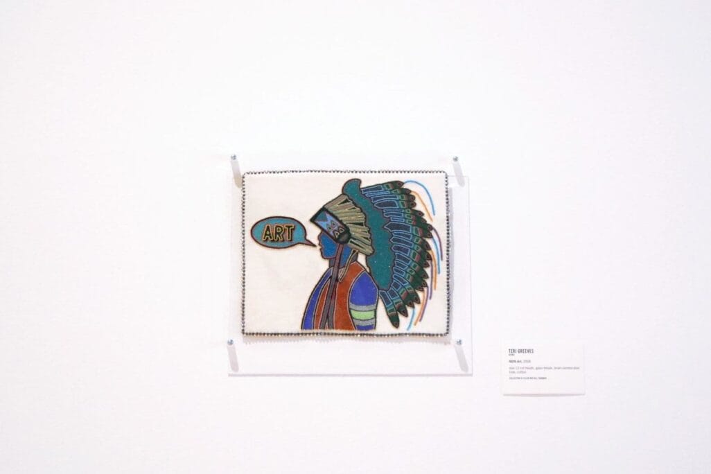 A framed artwork depicts a stylized profile of a figure wearing a detailed, colorful headdress, with the word 