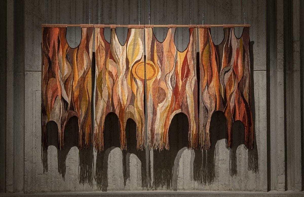 Uniquely shaped, large textile work hung on the wall featuring warm colours that relate to the title of the work.