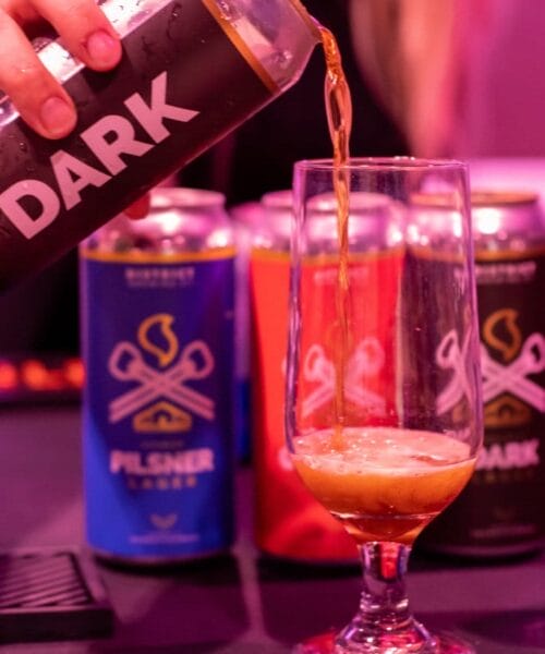 Person pouring beer from a can labeled 