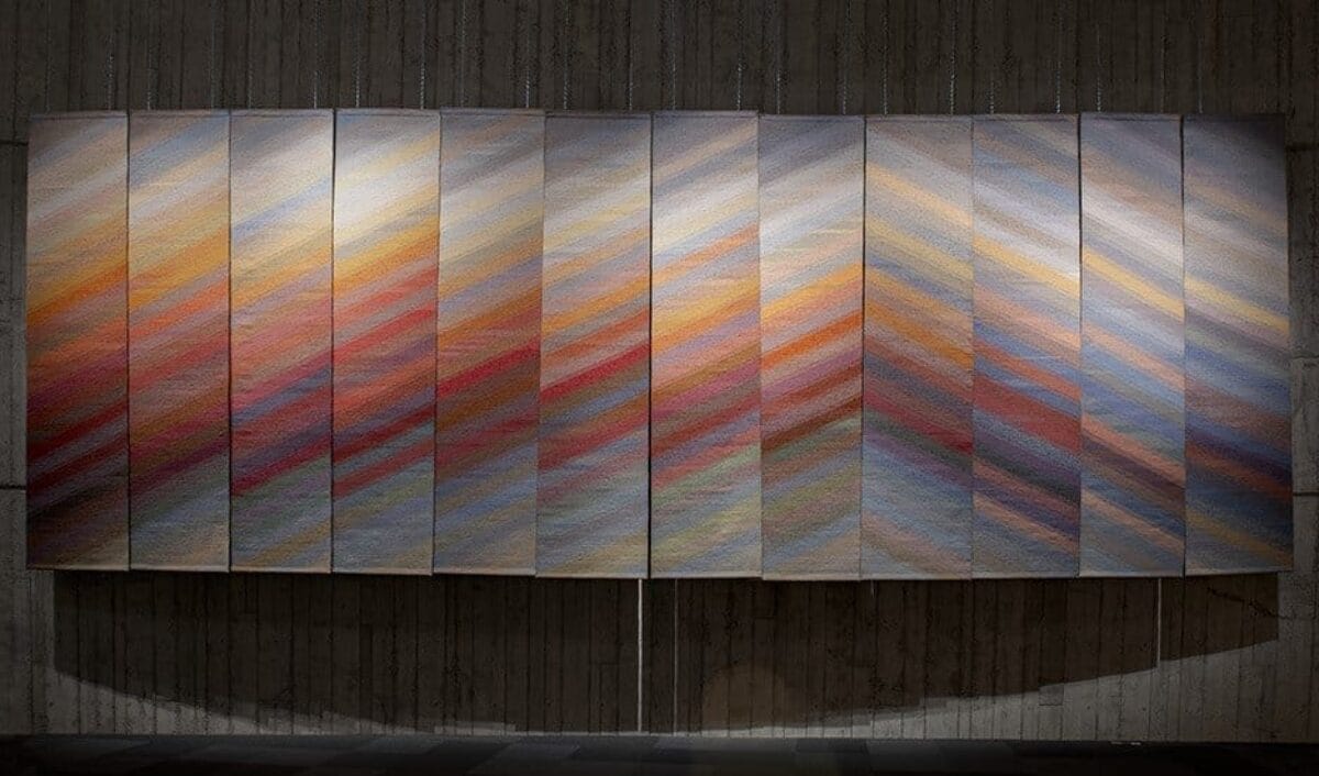Very large textile piece made of multiple panels hung on the wall.