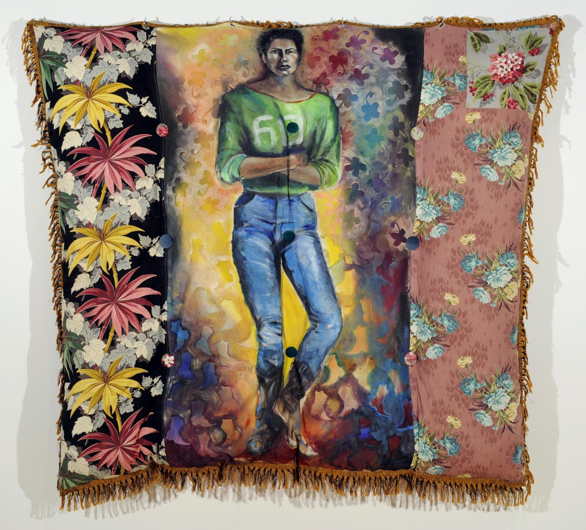 A mixed media artwork featuring a person with a painted number six jersey and blue jeans as the central figure. The backdrop includes vibrant floral and leaf patterns on fabric panels with frayed edges, blending into a colorful, abstract background.