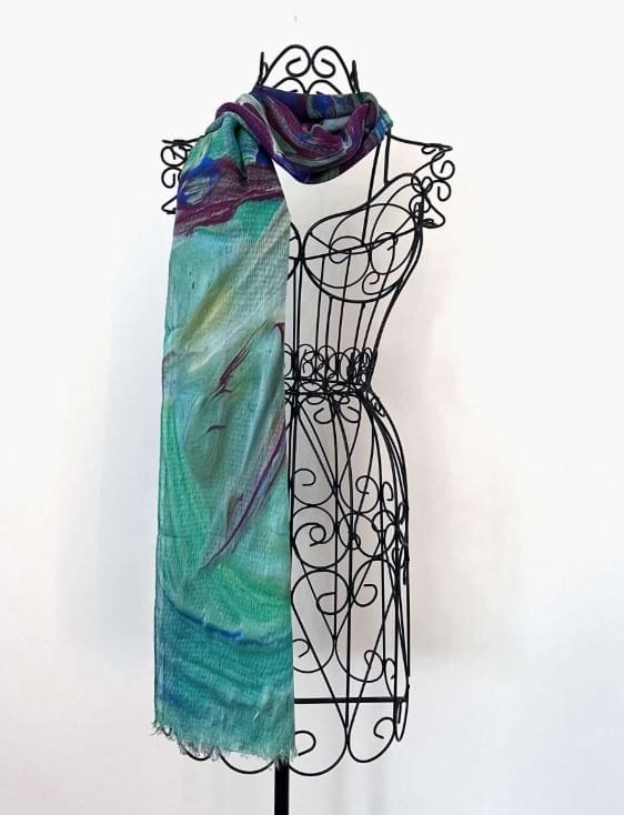 The Lariat Scarf by Kay Jay Studio, featuring an abstract pattern in teal, purple, and green, is displayed draped over a decorative black wire dress form against a plain white background.