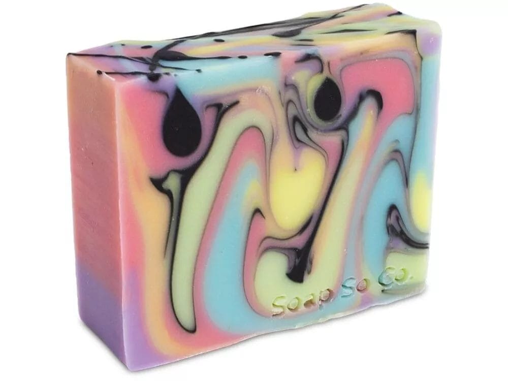 A rectangular bar of Soap So Co. featuring colorful, swirled patterns in shades of pink, blue, yellow, and black, with the brand name engraved on the side.