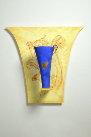 A decorative wall sconce features a vibrant blue elongated vase with a small cut-out, mounted on a fan-shaped yellow background with golden swirls. The artistic piece blends modern design with classical elements, highlighted against a plain white wall.