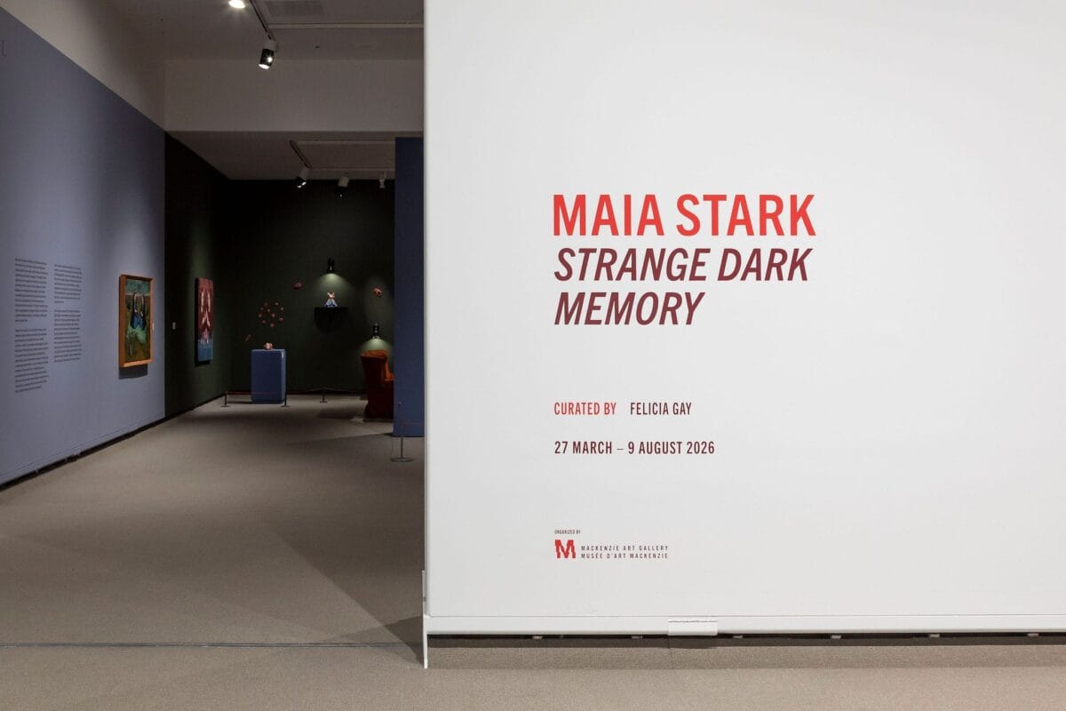 Entrance to an art gallery exhibition with a white wall displaying text: 