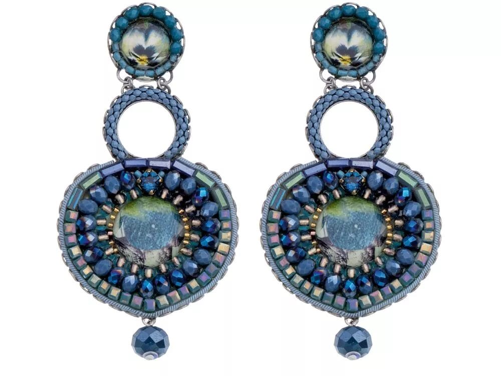 A pair of ornate, dangling **Earrings by Ayala Bar** featuring intricate blue and green beadwork. Each earring includes circular patterns and a central opalescent stone surrounded by various textured and shimmering beads, topped with a blue-green decorative stud.