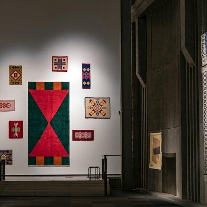 Textile works hung on the wall of a gallery.