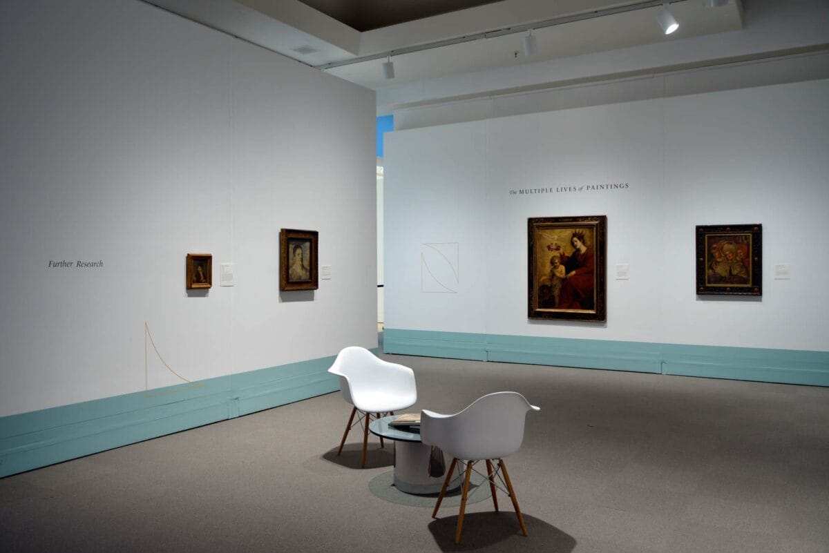 View of the Gallery room with three ornate frames on the walls and a small table with two chairs is seen in the middle of the room.